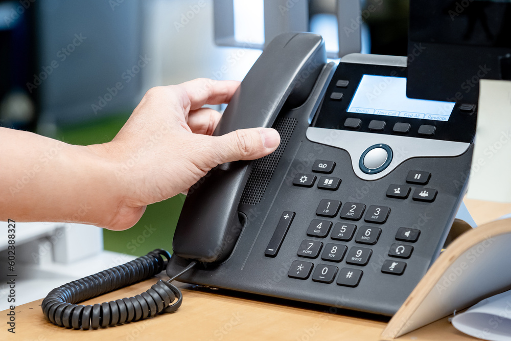 Call center and customer support. Operator hand trying to response customer call by using landline VoIP phone on help desk in the office. Call center and customer support. Operator hand trying to response customer call by using landline VoIP phone on help desk in the office.