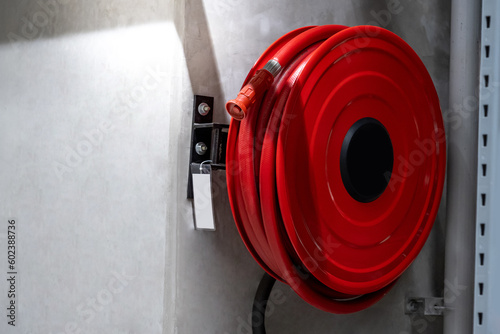 Red fire hose reel installed on the concrete wall in the factory or warehouse. Fire extinguisher equipment