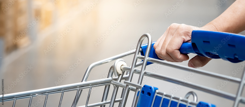 Customer hand holding shopping cart in grocery store or supermarket aisle. Customer hand holding shopping cart in grocery store or supermarket aisle.