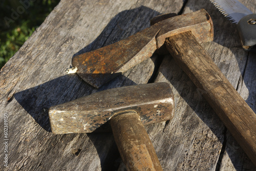 Old hammer with wooden handle, small ax and saw on wooden background. Rustic equipment working tools 