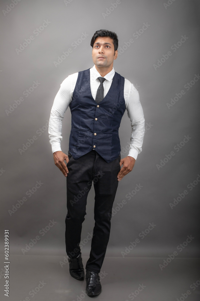Studio shot of cheerful, young, handsome Indian business man in formal wear against grey background. Male model. Fashion Portrait. Studio shot of cheerful, young, handsome Indian business man in formal wear against grey background. Male model. Fashion Portrait.