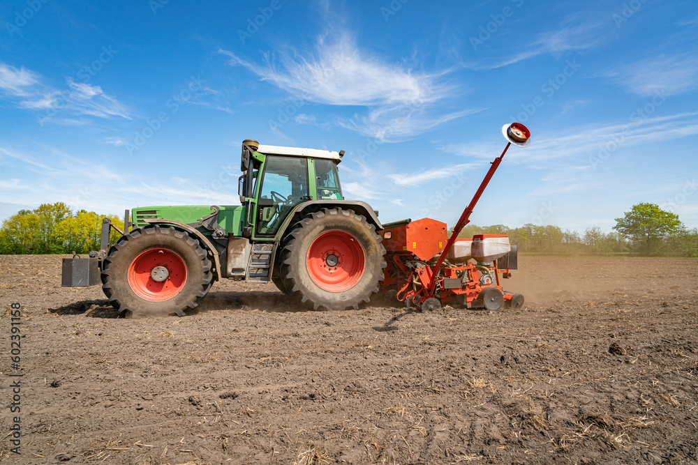 Grüner Trecker mit einer Maislegemaschine auf den Feld zwischen April und Mai. Grüner Trecker mit einer Maislegemaschine auf den Feld zwischen April und Mai.