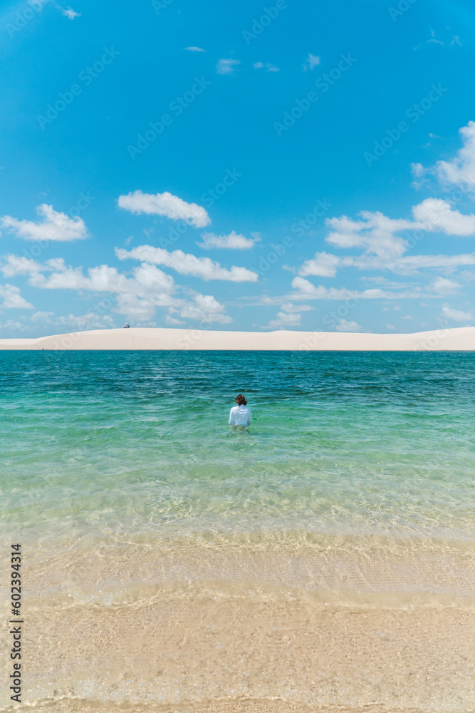 Brazilian woman in a blue lagoon with white sand in a national park in Brazil.