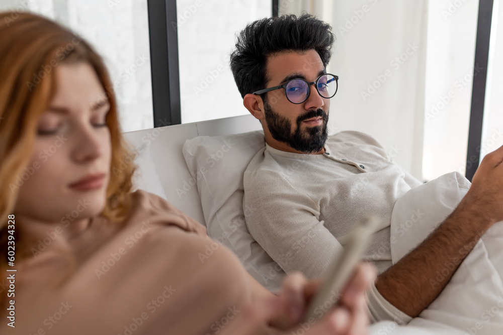 Couple with serious expression using smartphone lying on bed. Couple with serious expression using smartphone lying on bed.