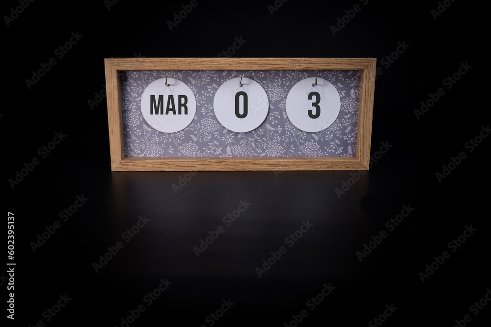 A wooden calendar block showing the date March 3rd on a dark black background, save the date or date of event concept. A wooden calendar block showing the date March 3rd on a dark black background, save the date or date of event concept.