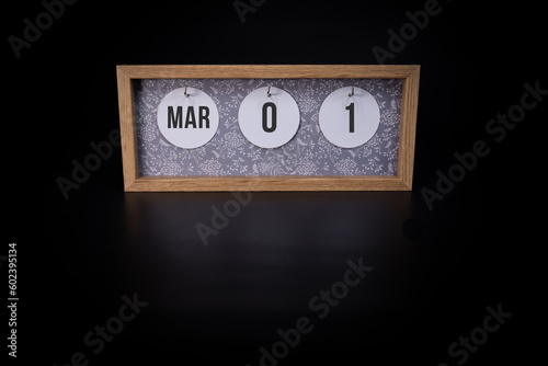 A wooden calendar block showing the date March 1st on a dark black background, save the date or date of event concept.