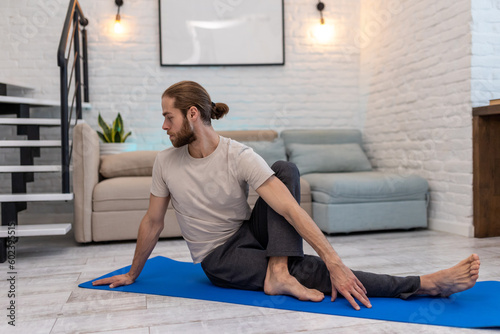 Man practicing yoga at home on floor on yoga mat stretching body.