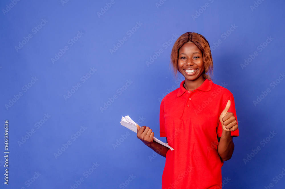 Beautiful young businesswoman holding folders while standing against grey background