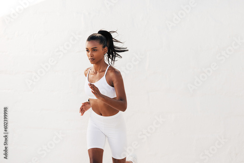 Fototapeta Naklejka Na Ścianę i Meble -  Slim woman in white fitness others running outdoors. Young slim fitness influencer jogging outdoors.