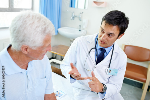 Doctor, senior man patient and talk with information, results and news with consulting health in retirement at clinic. Men, medic and consultation for wellness, healthcare and discussion in hospital © Anne B/peopleimages.com