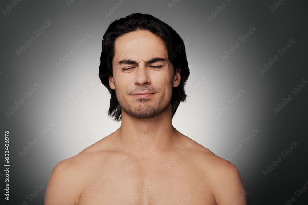 Portrait of frustrated young shirtless man keeping eyes closed against grey background Portrait of frustrated young shirtless man keeping eyes closed against grey background