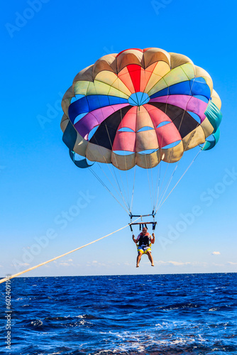 Parasailing water amusement - flying on a parachute behind a boat on a summer holiday by the sea. Summer vacation concept photo