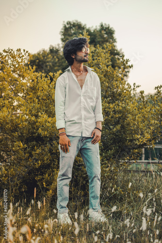 Portrait of a Handsome Indian man with long hair wearing sunglasses in White Shirt & Blue Jeans