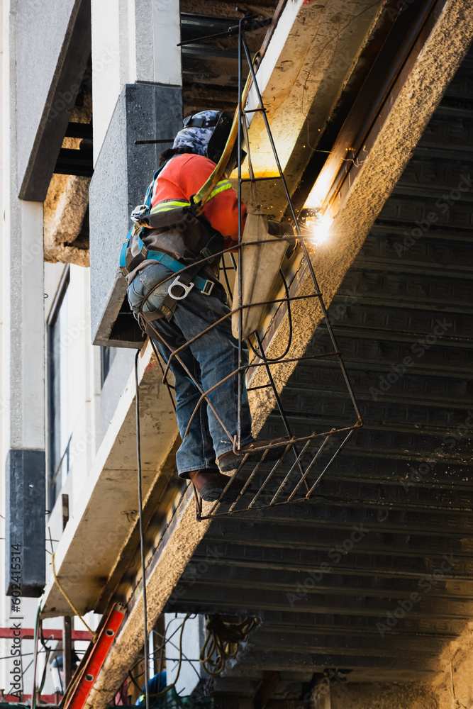Vertical Shot of Construction Worker Welding High Above in a Basket