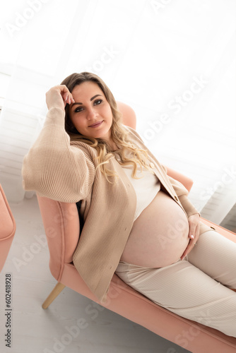 close-up of a pregnant woman on the bed hugging her pregnant belly. a beautiful pregnant woman lies on a sofa in a large beautiful living room near the window