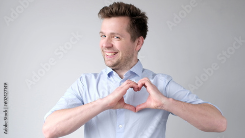 European young man shows a heart sign and confesses love photo