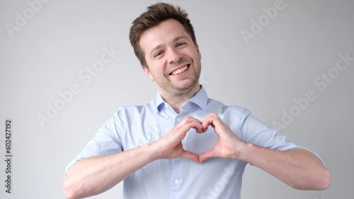 European young man shows a heart sign and confesses love photo