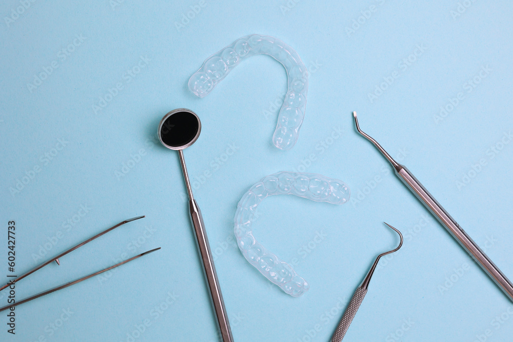 Transparent plastic aligners and dentist's tools on a colored background Transparent plastic aligners and dentist's tools on a colored background