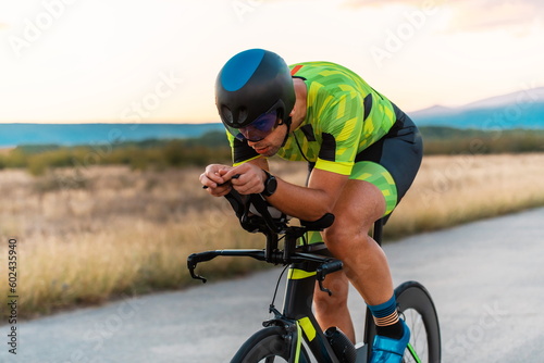  Close up photo of triathlete riding his bicycle during sunset, preparing for a marathon. The warm colors of the sky provide a beautiful backdrop for his determined and focused effort.