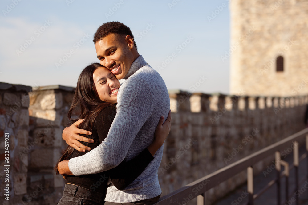 Multiracial couple posing on the walls of an old fortress. Man and woman in love.