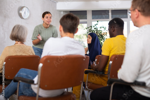 Young positive woman lecturing in front of multiethnic audience in office photo