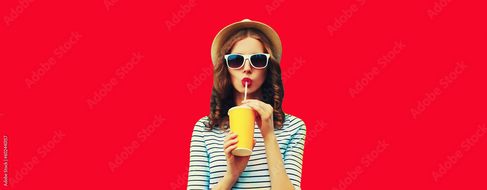 Portrait of stylish young woman drinking fresh juice wearing summer straw hat, sunglasses on red background - obrazy, fototapety, plakaty 