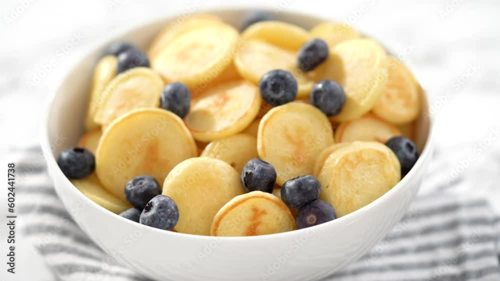 Step by step. Freshly made mini pancake cereal with fresh blueberries in a white bowl. Step by step. Freshly made mini pancake cereal with fresh blueberries in a white bowl.