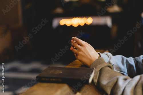Woman praying on her knees in an ancient Catholic temple to God. Hands folded in prayer concept for faith, spirituality and religion. Peace, hope, dreams concept