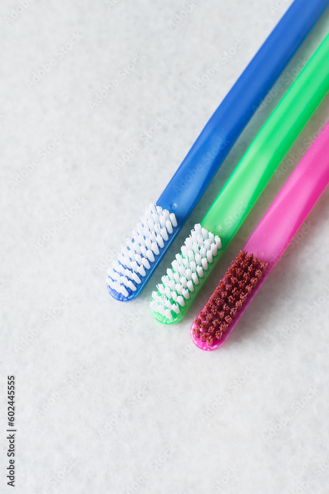 Blue, pink and green toothbrush with white bristles on a white background, colorful toothbrushes with copyspace Blue, pink and green toothbrush with white bristles on a white background, colorful toothbrushes with copyspace