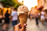 female hand of adult woman holding ice cream cone in hand, in city on summer day with more people in background