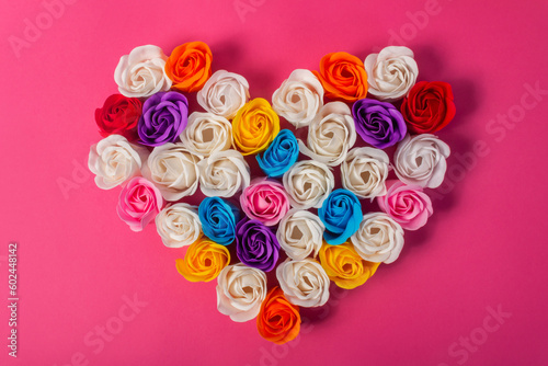 A big floral heart made of multicolored soap roses on pink background, top view. Beautiful decoration for Valentine's Day. The concept of love, skin care, beauty, Valentine's Day.