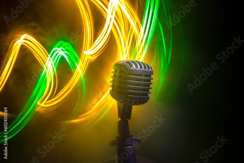 Microphone for sound, music, karaoke in audio studio or stage. Mic technology. Speech broadcast equipment. Microphone in dark room on table with backlight. Selective focus