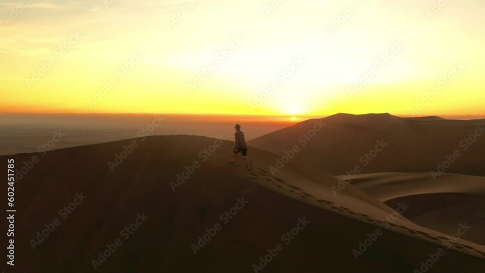 Travel, desert and silhouette of man at sunset for summer break, global and exotic trip. Abroad, adventure and journey with guy walking on sand dunes of Namibia for freedom, vacation and landscape Travel, desert and silhouette of man at sunset for summer break, global and exotic trip. Abroad, adventure and journey with guy walking on sand dunes of Namibia for freedom, vacation and landscape