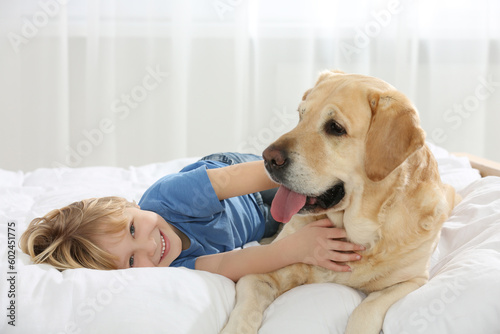 Cute little child with Golden Retriever on bed. Adorable pet