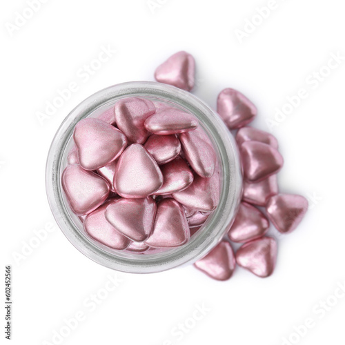 Glass jar and delicious heart shaped candies on white background, top view