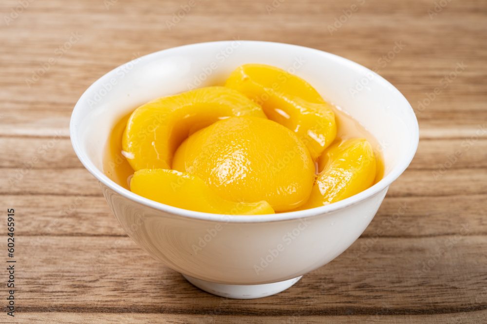 angle view bowl of yellow peach syrup on wood background angle view bowl of yellow peach syrup on wood background