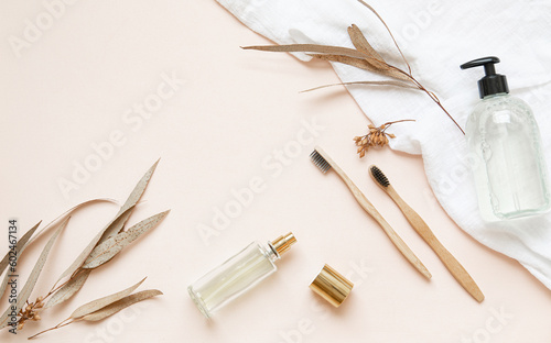 Bamboo toothbrush on a table with copy space on a pink background. Styled composition of flat lay with dried eucalyptus leaves.