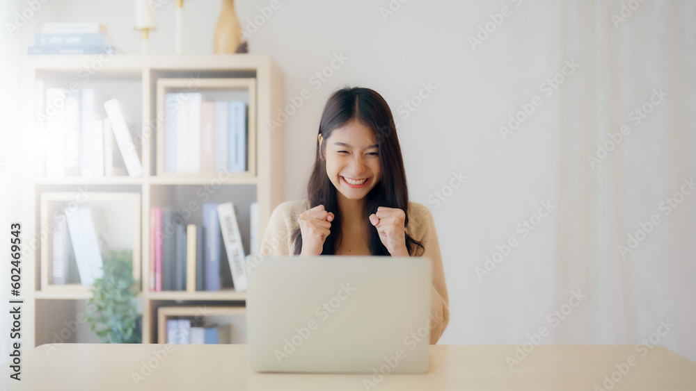 Funny euphoric young asian woman celebrating winning or getting ecommerce shopping offer on computer laptop. Excited happy girl winner looking at notebook celebrating success Funny euphoric young asian woman celebrating winning or getting ecommerce shopping offer on computer laptop. Excited happy girl winner looking at notebook celebrating success