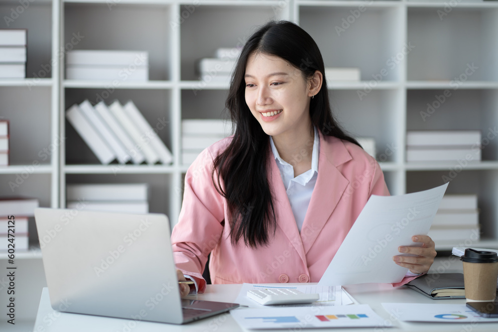 Young smart Asian businesswoman focusing on her project while working on laptop computer.