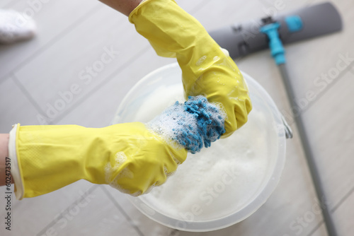 Obraz na płótnie Janitor in rubber gloves wrings mop rag over bucket w salonie