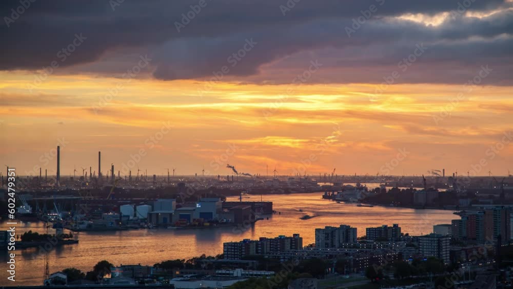 Stunning timelapse of Rotterdam's industrial skyline and cargo port in the Netherlands, captured during a cloudy autumn evening with a vibrant, golden sunset as the backdrop. Stunning timelapse of Rotterdam's industrial skyline and cargo port in the Netherlands, captured during a cloudy autumn evening with a vibrant, golden sunset as the backdrop.
