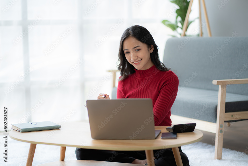 beautiful Asian girl wearing red sweater working with laptop computer in the living room. beautiful Asian girl wearing red sweater working with laptop computer in the living room.