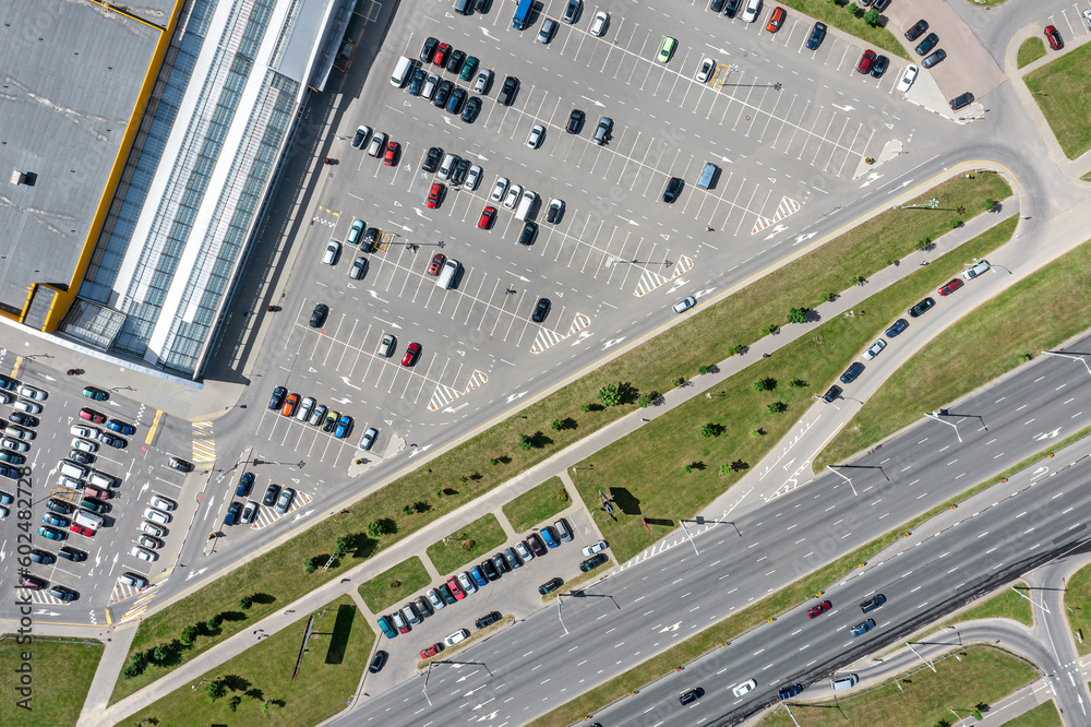 shopping mall parking lot with many parked cars. top view aerial photo in sunny summer day.