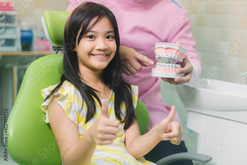 Portrait of happy girl shows thumb up gesture at dental clinic