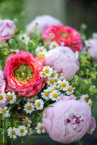 Blumenstrauss mit Pfingstrosen und Rosen in Rosa und Pink auf einem Holzstamm im Garten, natürlich arrangierte Blumen im Strauß, 