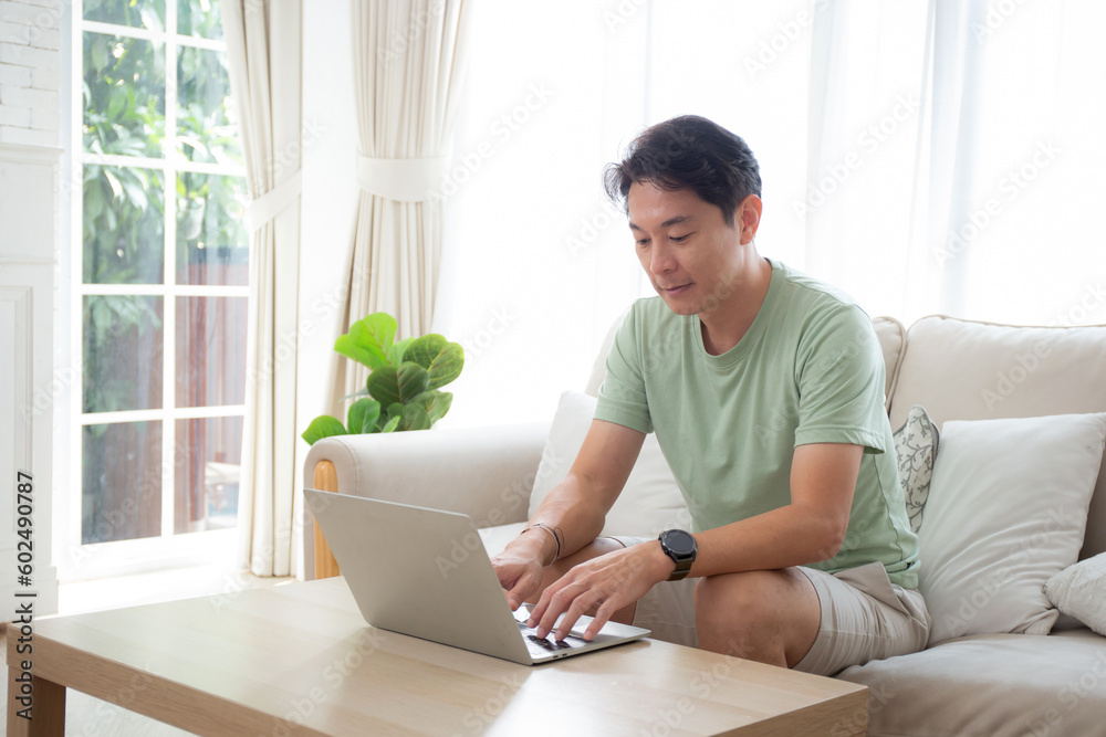 Young asian man typing keyboard on laptop computer on desk at home, businessman working to internet online, freelance male using notebook on table, communication and lifestyle concept. Young asian man typing keyboard on laptop computer on desk at home, businessman working to internet online, freelance male using notebook on table, communication and lifestyle concept.