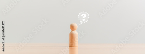 Wooden figurine as person who have questions and need help solving the problems. Man has no idea on wood table. Business marketing and Creative solution concept. photo