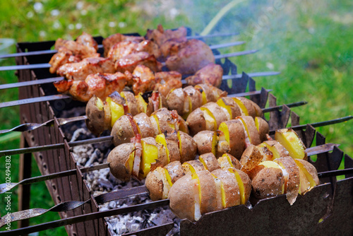 An array of kebabs skewers and potatoe with bacon are cooked on portable metal braziers