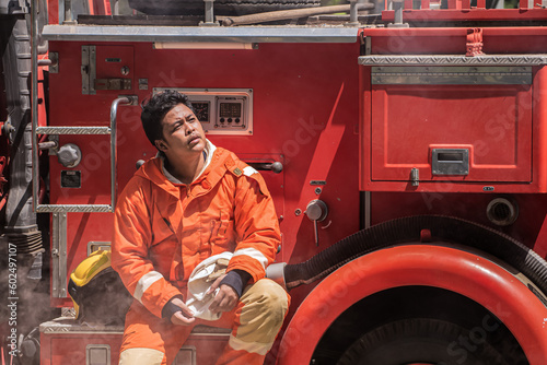 Valokuva As he sits back against the fire truck the firefighter gazes upward his eyes tracing the expanse of the sky perhaps seeking solace or finding a moment of reflection amidst the chaos