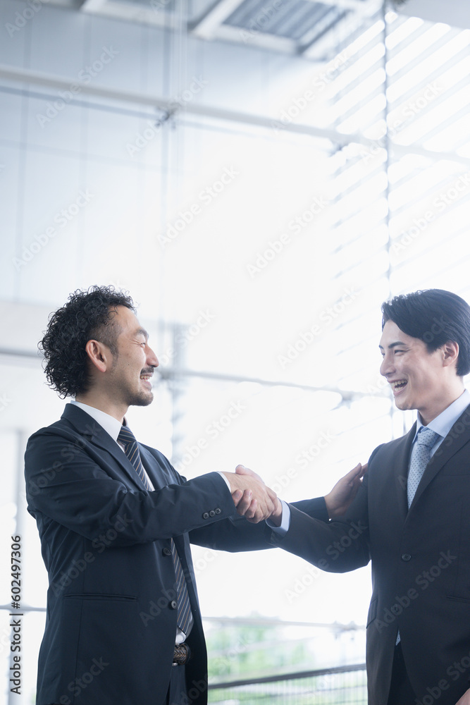 Successful business image of shaking hands, contract signing, cooperation, etc. Cool Asian man in a suit vertical backlight Successful business image of shaking hands, contract signing, cooperation, etc. Cool Asian man in a suit vertical backlight